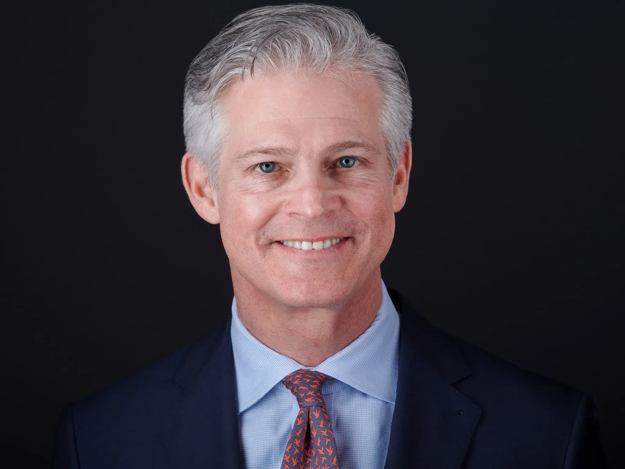 Professional headshot with full head in frame — eyes centered, empty space above hairline, face occupies less than half the image