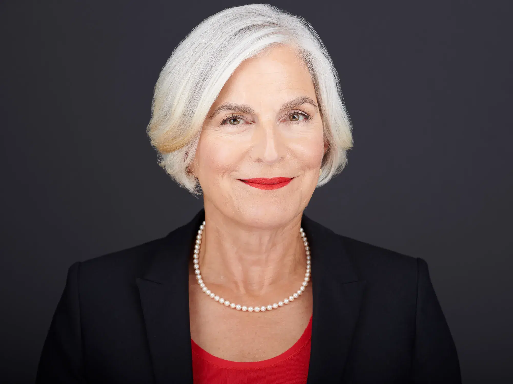 Landscape orientation professional headshot preserving full shoulders — subject looks composed, grounded, and authoritative