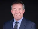 Headshot of a man with gray hair in a navy suit and dotted tie, by Damon Bates Photography